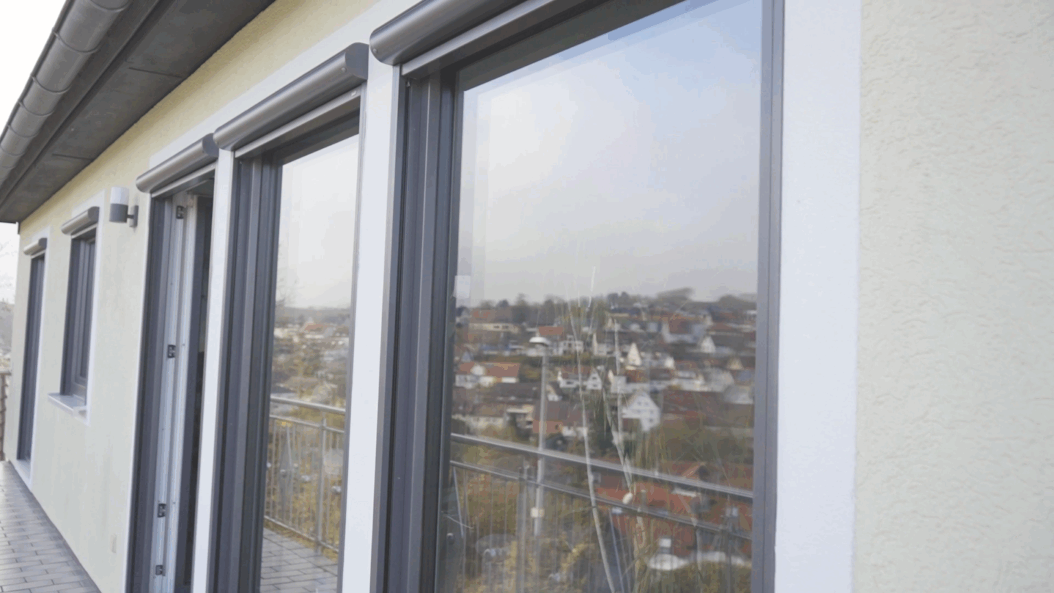 Fenster-13 Moderne Glasschiebetüren auf Balkon mit Stadtblick im Hintergrund.