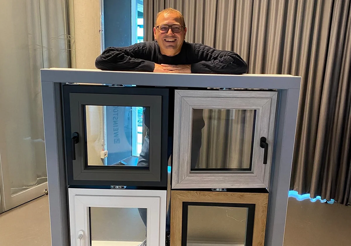 Markus Lieber 2025 in seinem Showroom Mann präsentiert innovative Fensterdesigns in unterschiedlichen Farben und Materialien, die vor einem Vorhang ausgestellt sind.